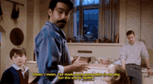 a man is talking to a child in a kitchen while another man watches .