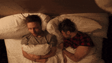 two men are laying in bed holding hands