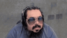 a man with a beard and sunglasses is wearing headphones .
