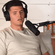 a man wearing headphones talks into a microphone while sitting on a couch