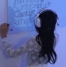 a woman wearing headphones is writing on a blue board that says captain kraku