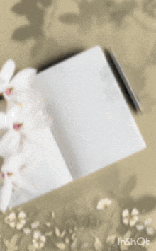 a notebook is open to a page with a pen and flowers in the background