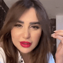 a close up of a woman 's face with red lips and a piercing in her lip .