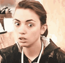 a close up of a woman making a funny face while wearing a black jacket .
