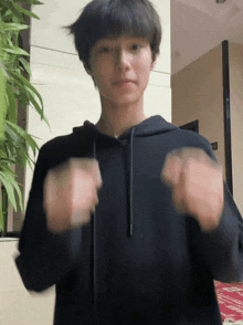 a young man in a black hoodie is making a fist