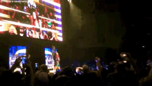 a crowd of people are watching a wrestling match on a large screen with the words " the next big thing " on the bottom