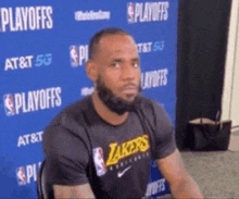 a man wearing a lakers shirt is sitting in front of a blue wall