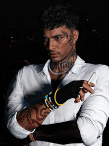 a man with a tattoo on his face is wearing a white shirt