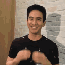 a man in a black shirt is smiling and making a fist gesture