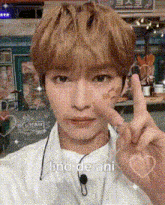 a young man is giving a peace sign with his finger .