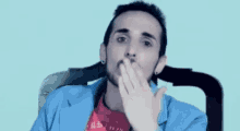 a man with a beard is blowing a kiss with his hand .