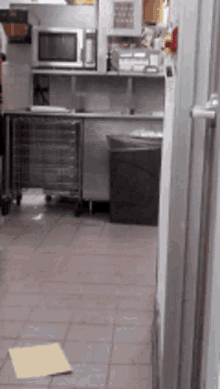 a kitchen with a microwave and a trash can on the floor