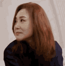 a woman with red hair is sitting on a bed and looking at the camera .