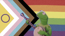 kermit the frog holding a banjo in front of a rainbow flag