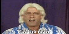 a man with blonde hair is standing in front of a microphone and says `` i 'm the man ! ''