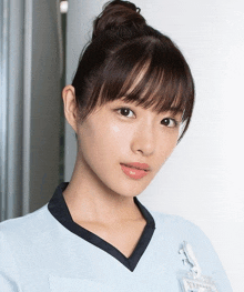 a woman wearing a blue scrub top has a name tag on her neck that says ' a ' on it