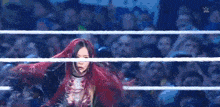 a woman with red hair is standing in a wrestling ring in front of a crowd of people .