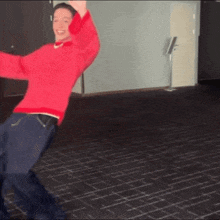 a man in a red sweater is dancing on a black tiled floor .