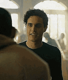 a man with curly hair is standing next to another man in a room .