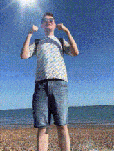 a man wearing a t-shirt that says adidas on it is standing on a beach