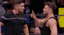 two men are fighting in a wrestling ring while a crowd watches .