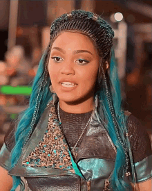 a woman with blue hair is wearing a leather jacket and necklace