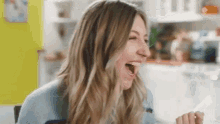 a woman is laughing with her mouth open while sitting at a table .