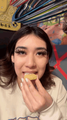 a woman is eating a snack in front of a sign that says ' boi ' on it