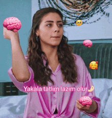 a woman in a pink shirt is holding two pink brains in her hands
