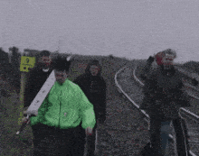 a man in a green jacket is talking to a group of people