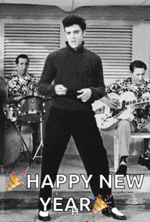 elvis presley is dancing in a black and white photo with a band behind him .