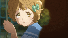 a girl with a green bow on her head is looking out a window