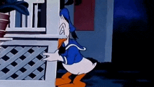 donald duck is standing next to a fence in front of a house .