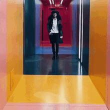a man is walking down a hallway with a yellow floor