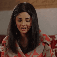 a woman with dark hair is wearing a red and grey jacket