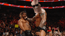 two wrestlers are dancing in front of a crowd and a sign that says raw