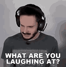 a man wearing headphones and a black shirt is asking what are you laughing at .