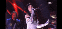 a woman singing into a microphone on a stage with the number 63 on the bottom