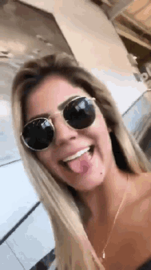 a woman wearing sunglasses is sticking out her tongue