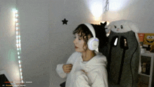 a woman wearing headphones stands in front of a stuffed animal