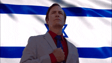 a man in a suit and tie stands in front of a flag