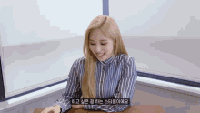 a woman in a striped shirt is smiling and sitting at a desk