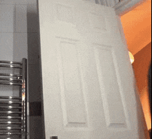 a white door is open in a bathroom with a towel rack in the background