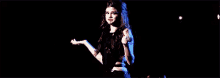 a woman in a black dress is dancing on a stage .