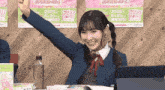 a girl sitting at a table with her fist in the air in front of a poster that says 2025