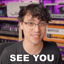 a man wearing glasses and a black shirt with the words see you on it