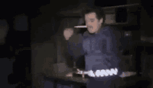 a man in a blue shirt is standing in the dark .
