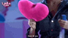 a woman is holding a pink heart shaped pillow next to a blue bottle .