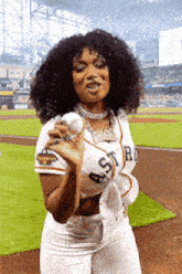 a woman in an astros jersey is holding a baseball in her hands