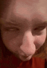 a close up of a person 's face with their eyes closed and a red shirt on .